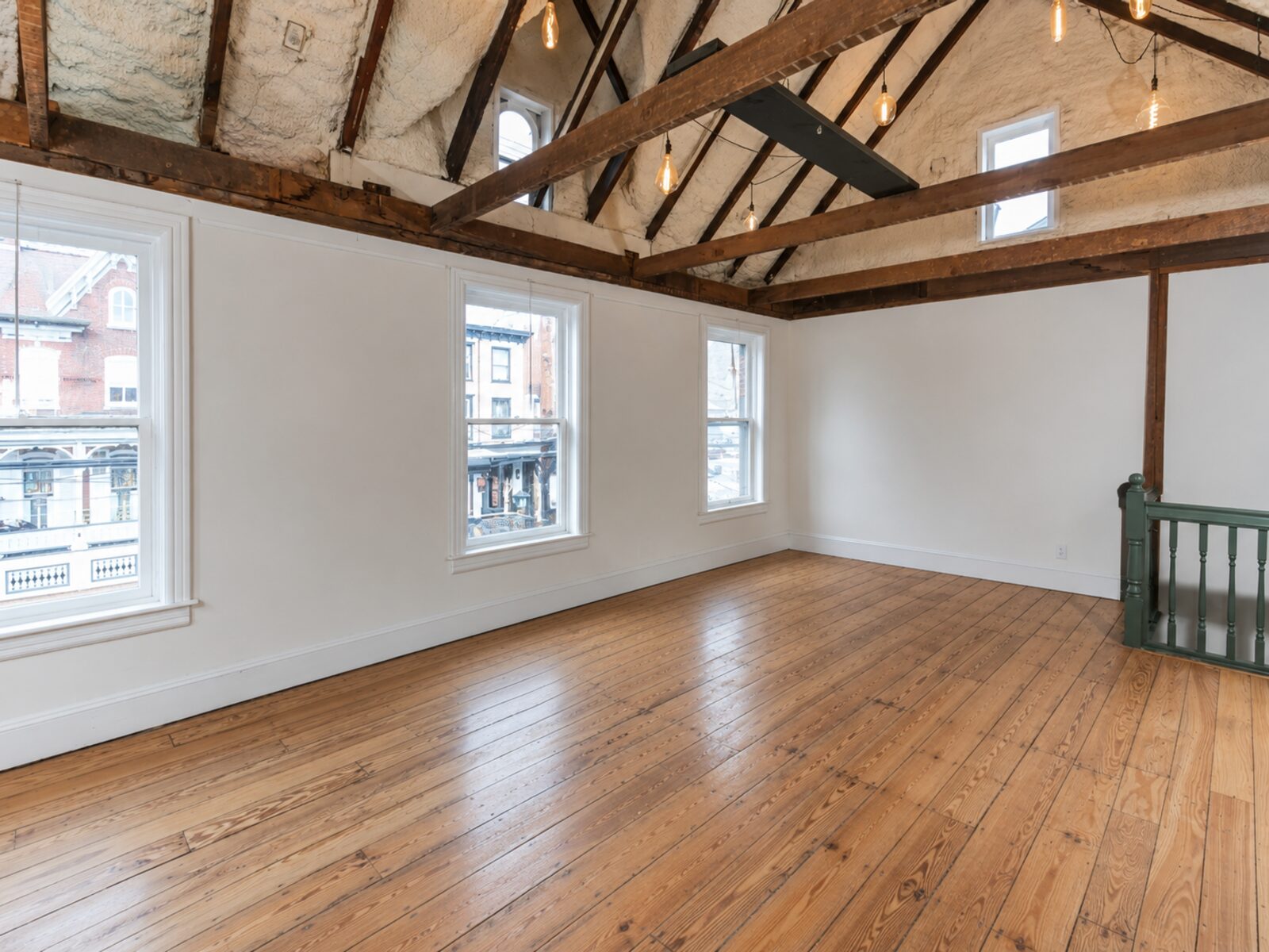 Great Hall with exposed timber ceiling, pendant lights, large windows, and wood floor.