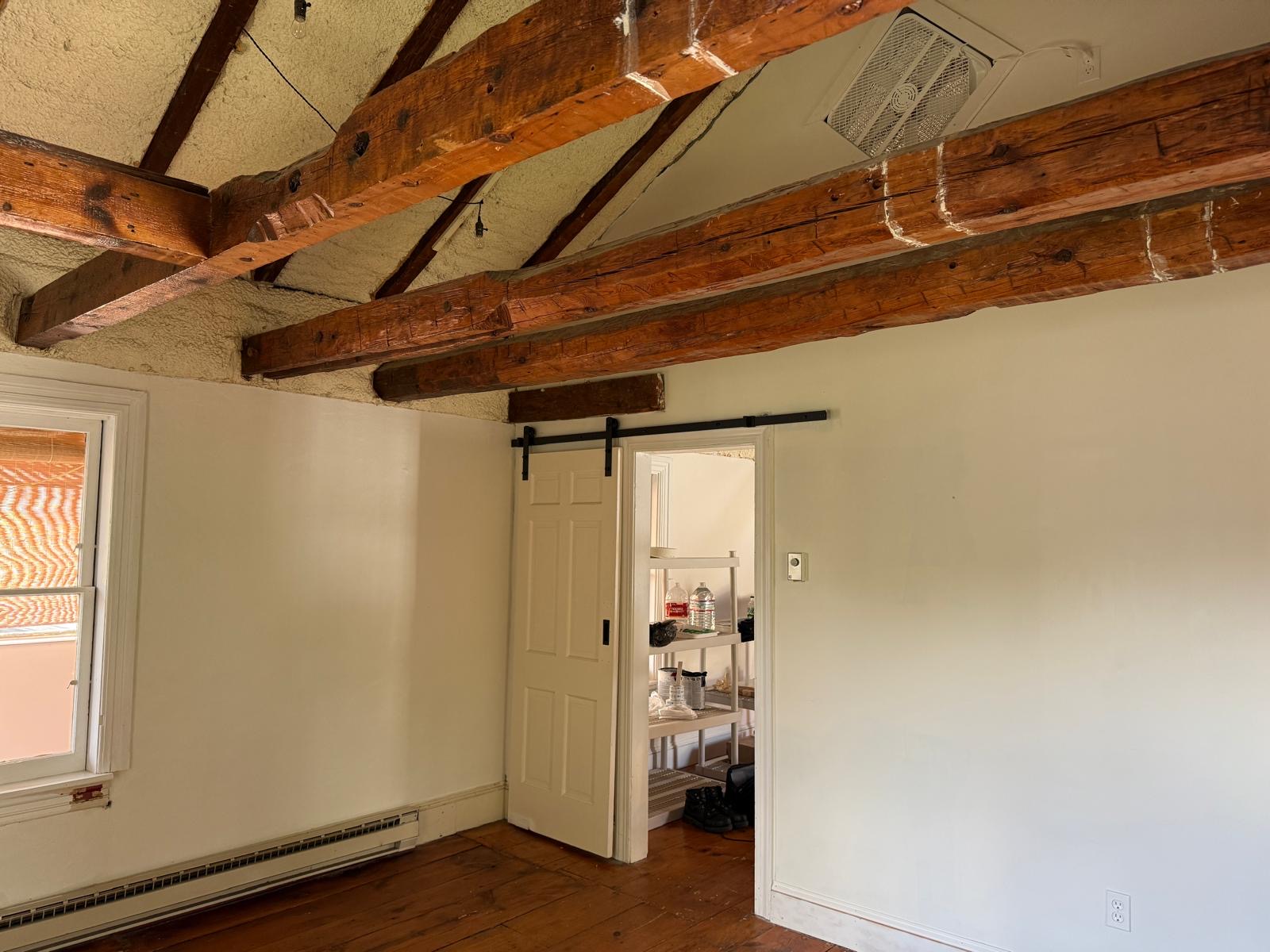 Private office studio with exposed timber beams, wood floors, and a sliding door.